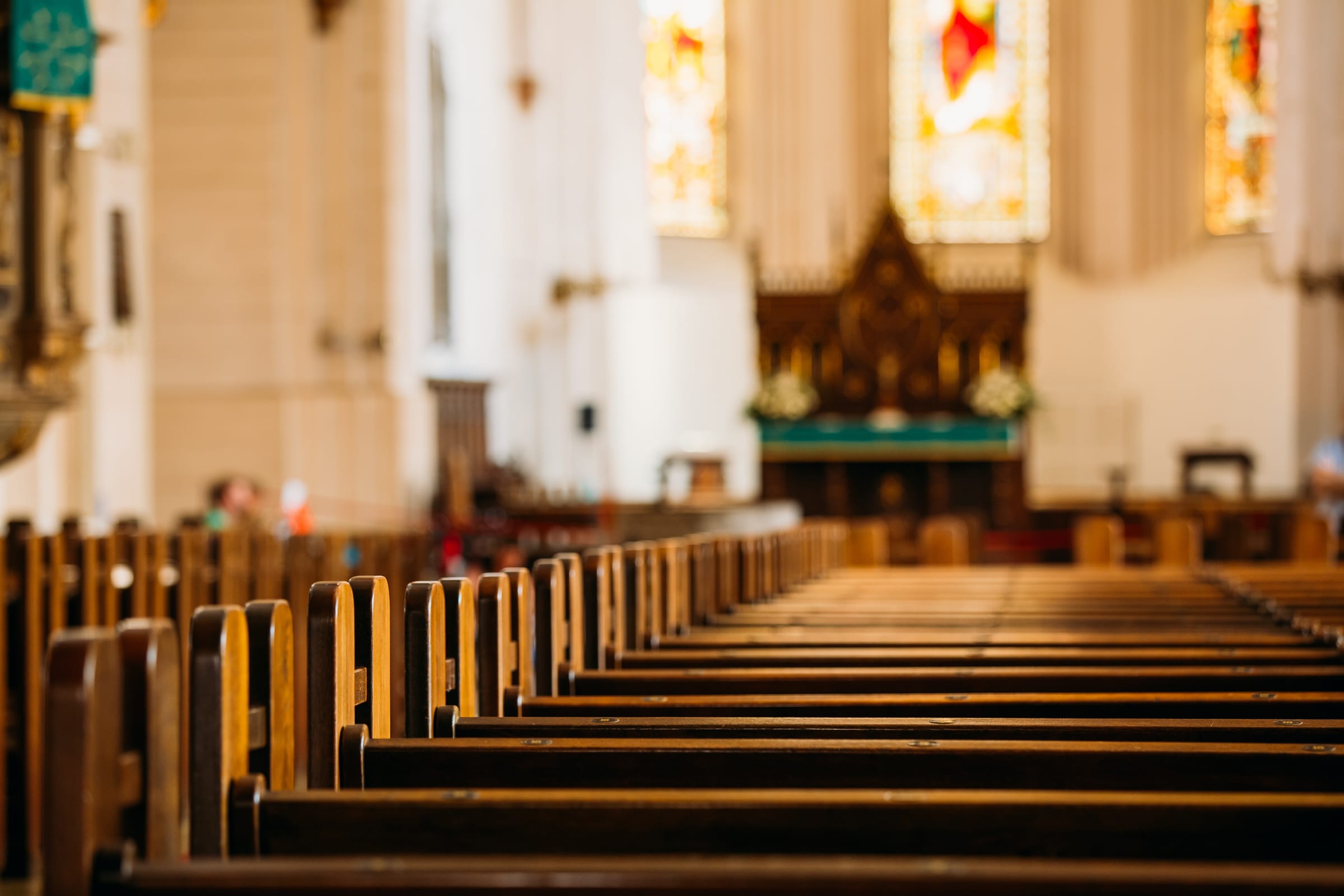 Wnętrze kościoła — ławki, witraże i ołtarz główny w głębi